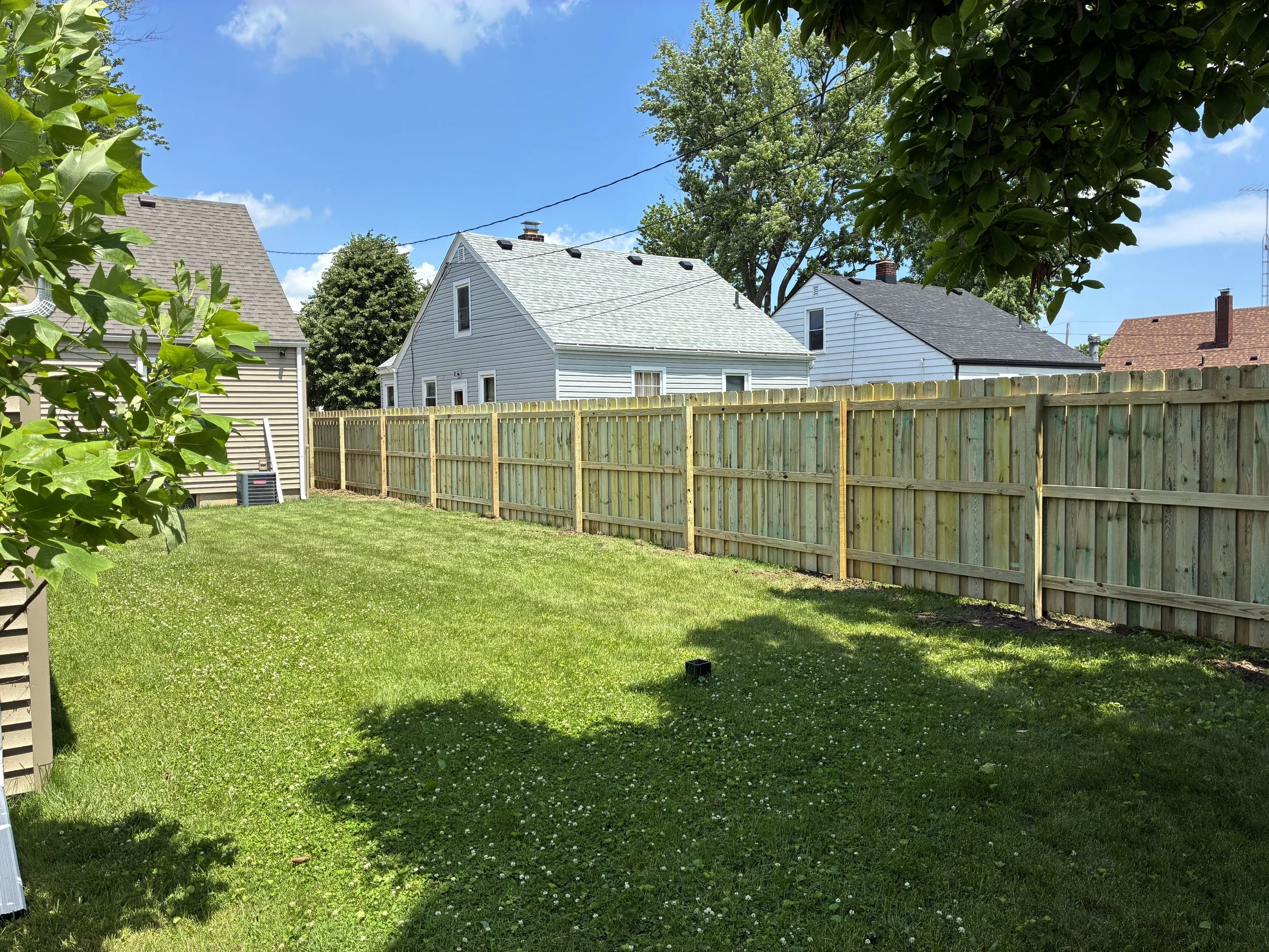 Clean residential backyard with a green lawn and a new wood privacy fence