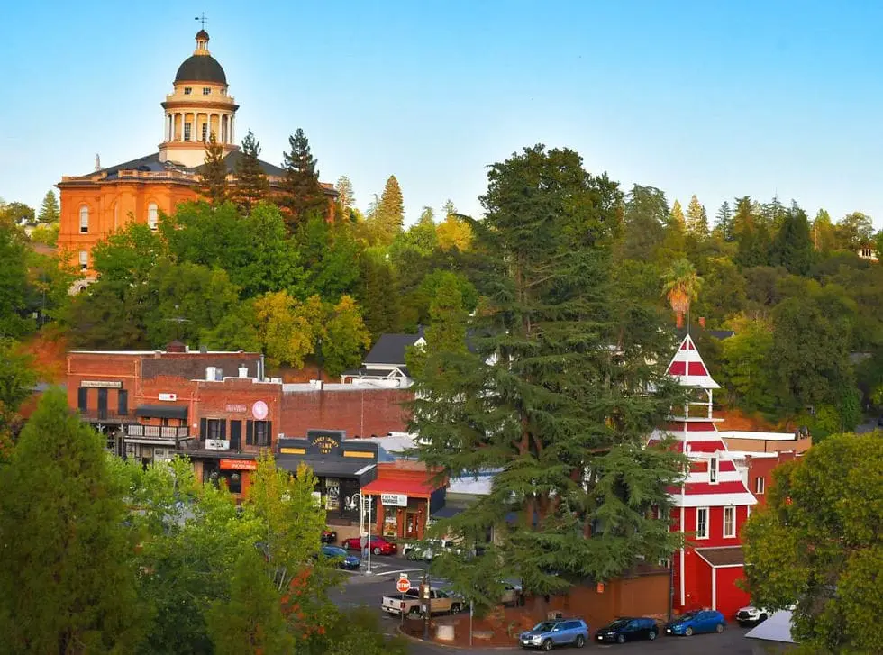 Historic Placer County Courthouse on a tree-covered hill above the brick storefronts of downtown Auburn, California