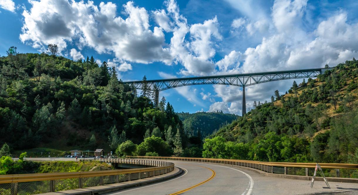 Foresthill Bridge spanning a forested canyon near Auburn, California, with a curving road in the foreground