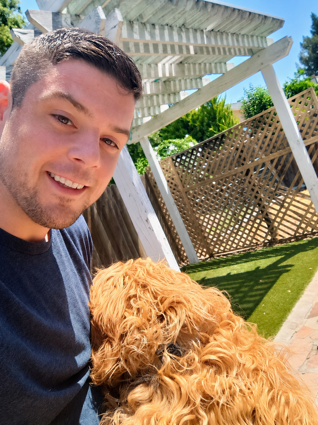 Adam, owner of The Poop Scoop Co., with his golden doodle in a backyard