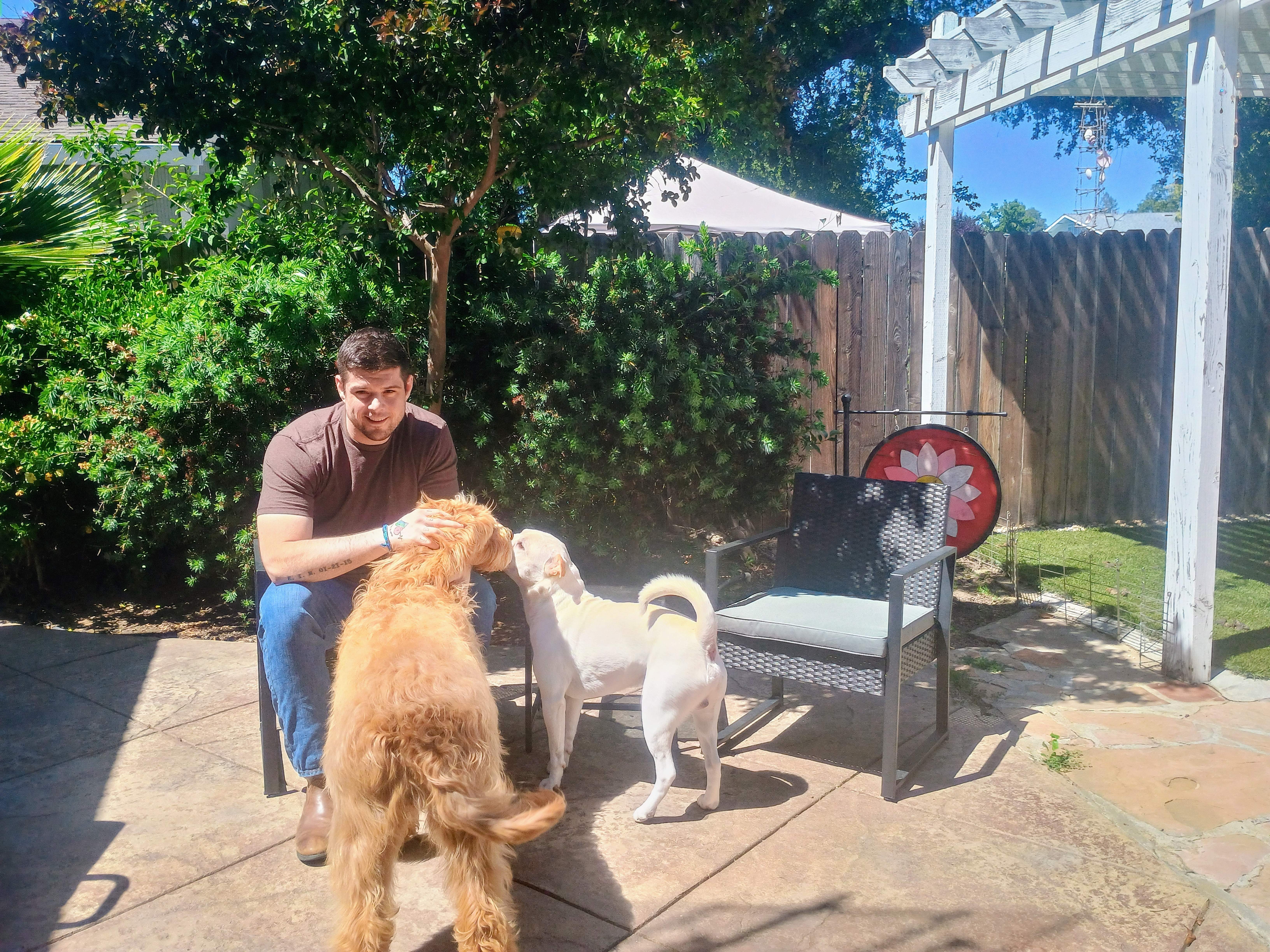 Adam, owner of The Poop Scoop Co., sitting outside with his two dogs